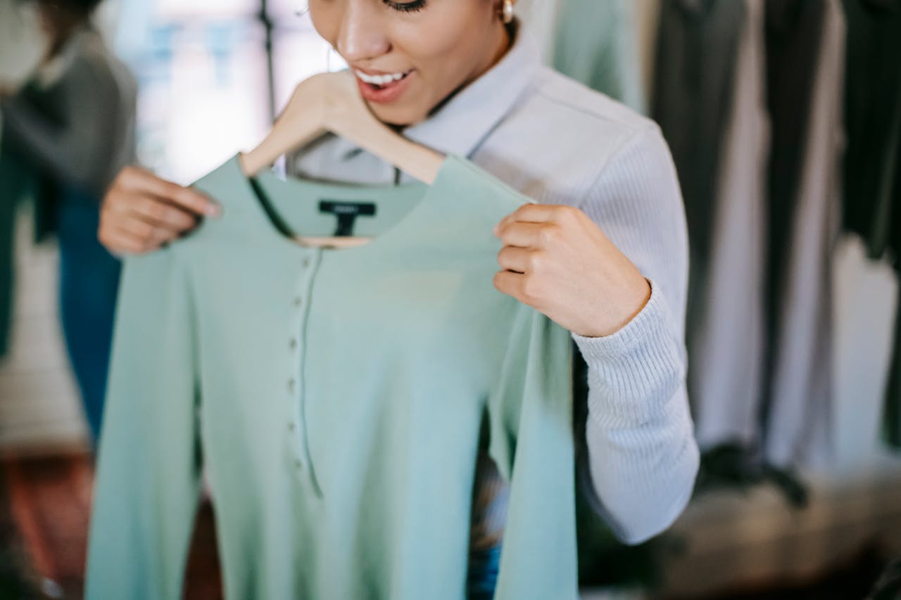Mastering the First Impression: Your intriguing post title goes here Crop unrecognizable smiling woman in trendy outfit choosing clothes in light shop with blue blouse on hanger in hands